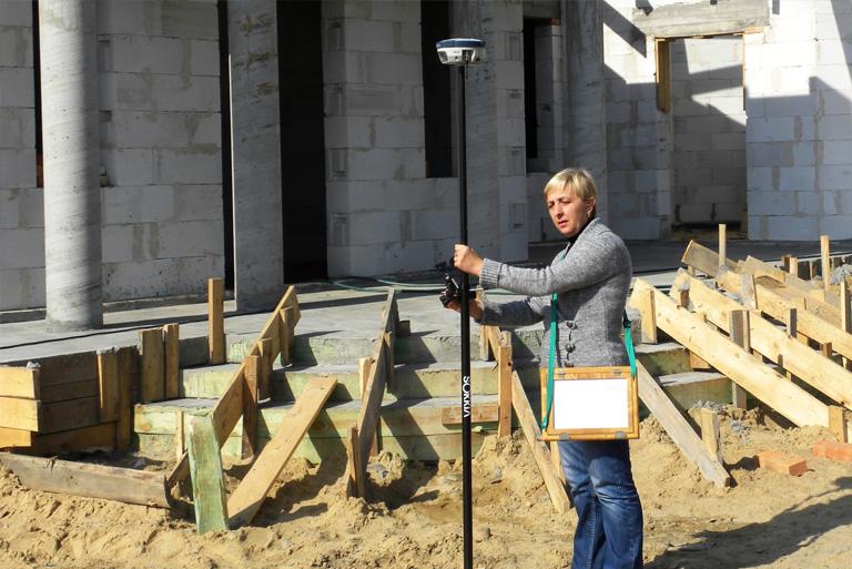 kobieta na budowie domu trzymająca przyrząd do pomiarów geodezyjnych